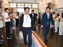 多くの人たちがいる中を男性2名が並んで歩いている写真